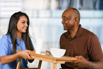 Health care worker serving a meal to an elderly patient